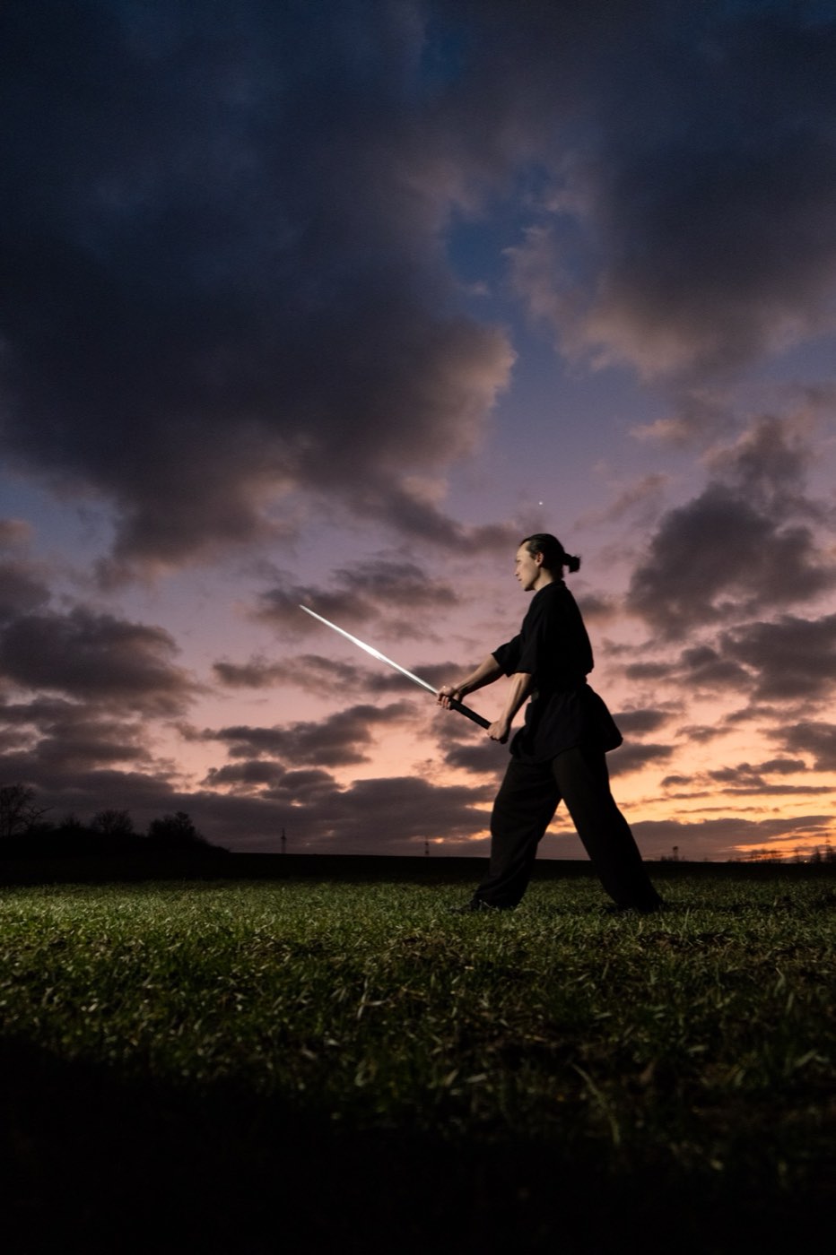 Eike Opfermann at dusk, mid-stance, holding a straight sword